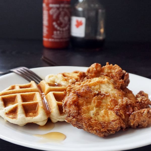 Crispy fried chicken and waffles drizzled with syrup on a white plate at Outpost 611 Eatery.